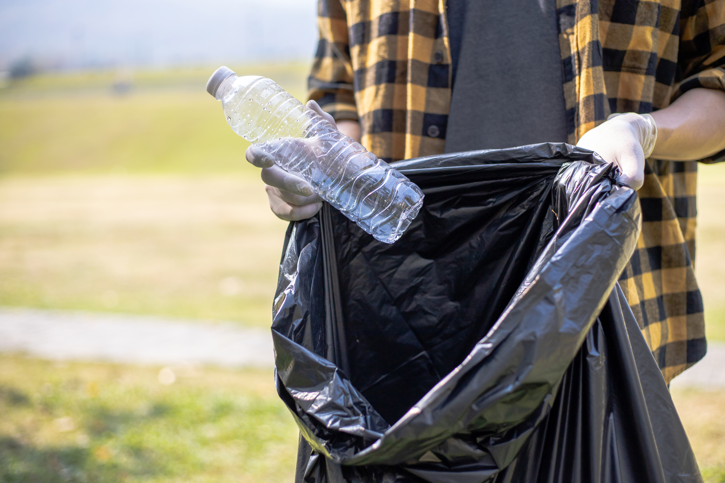 Person Throwing Plastic Bottle on Bag 